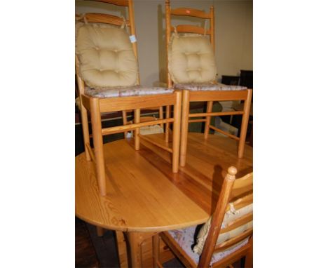 An Ercol pine dining suite comprising extending dining table with fold-out leaf, set of six ladderback chairs, and an associa