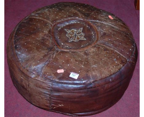 A tan leather pouffe of circular form with floral embroidered detail