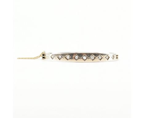 An antique gold &amp; diamond bangle bracelet. The bangle set with nine graduating old round cut diamonds in rhombus settings