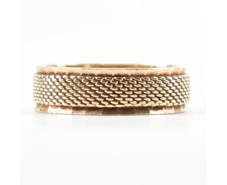 A hallmarked 9ct gold band ring. The ring of Milanese mesh encompassed by faceted borders. Hallmarked for London 1971, makers