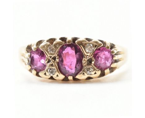 A hallmarked 9ct yellow gold, ruby &amp; diamond ring. The ring having a central oval cut purple red ruby flanked by two roun