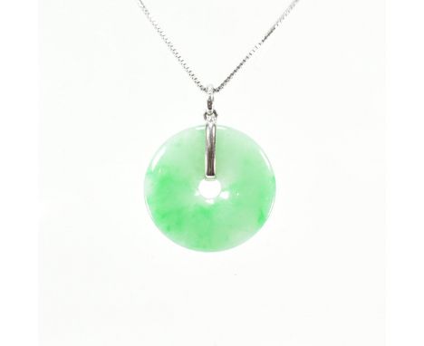 An 18ct white gold &amp; jade pendant &amp; necklace chain. The pendant of mottled green hard stone in a disc to white gold b