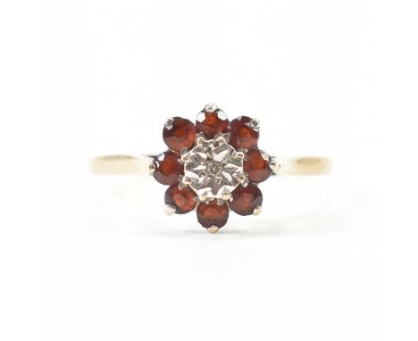 A hallmarked 9ct yellow gold, garnet &amp; diamond cluster ring. The ring having a central illusion star set accent diamond s