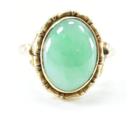 A vintage 14ct yellow gold &amp; jade dress ring. The ring having a bezel set oval cut mottled green hard stone cabochon to b