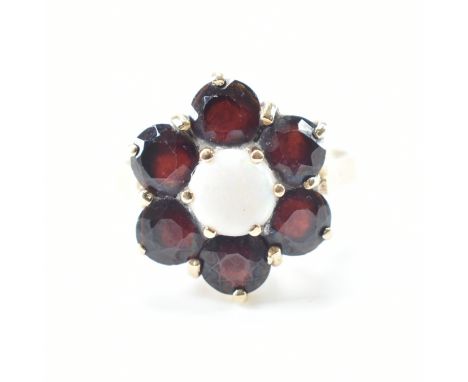 A hallmarked 9ct yellow gold, garnet &amp; opal cluster ring. The ring having a central round cut opal cabochon surrounded by