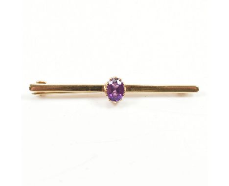 A hallmarked 9ct yellow gold & amethyst bar brooch pin. The brooch having a central oval cut prong basket set purple amethyst