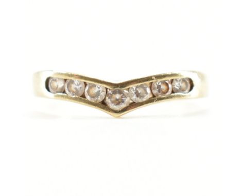 A hallmarked 9ct yellow gold &amp; cubic zirconia seven stone ring. The ring of chevron wishbone form having seven round cut 