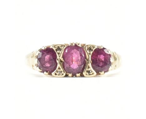 A 9ct yellow gold, ruby &amp; diamond ring. The ring having three graduated oval cut rubies with four accent diamonds spaced 