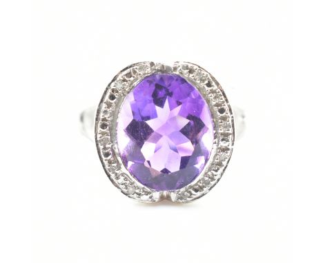 A French 18ct white gold amethyst and diamond cocktail ring. The ring set with an oval cut amethyst framed by single cut diam