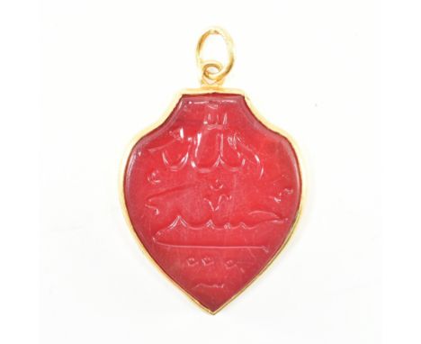 A Chinese marked gold &amp; ruby glass intaglio pendant. The necklace pendant of ruby glass in a shield form being carved wit