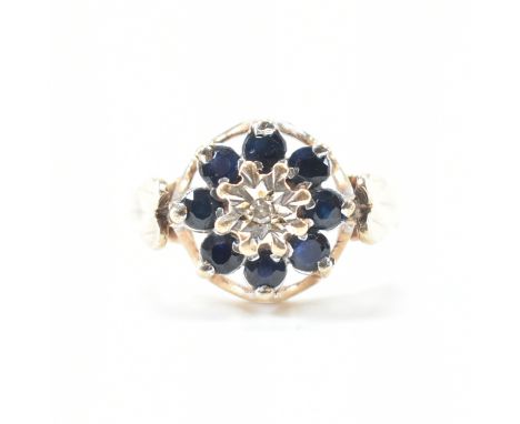 A hallmarked 9ct yellow gold, sapphire &amp; diamond cluster ring. The ring having a central illusion star set accent diamond