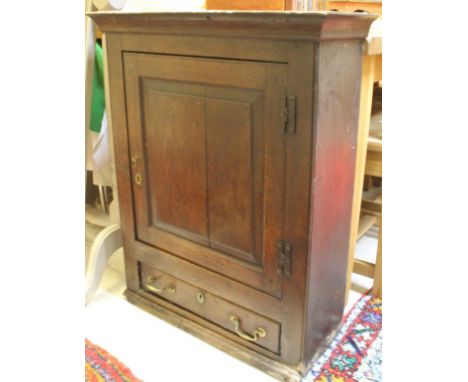 A Georgian oak wall cabinet with shaped pediment above a single panelled door opening to reveal a shelf lined interior above 