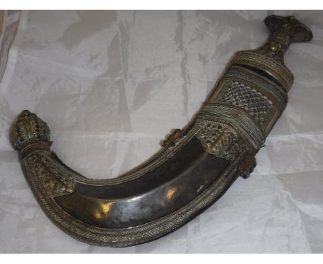 A late 19th or early 20th Century Omani jambiya (dagger) in white metal and leather mounted scabbard with white metal handle 