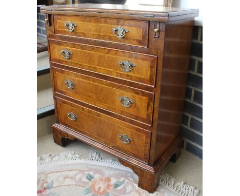 A walnut and banded bachelor's chest with fold-out top above four graduated drawers, raised on bracket feet