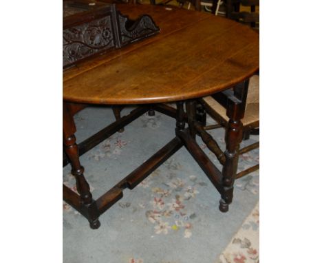 An early 20th Century oak gate-leg dining table with baluster turned supports and stretchered base