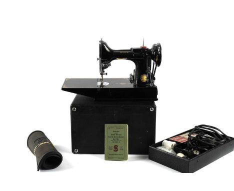 A Singer 221k electric sewing machine, with manual, mat, and accessories, contained in a carry case.