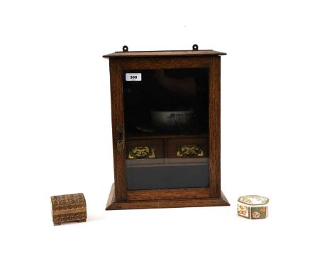 A George III style oak smokers cabinet, with glazed panel door, opening to reveal a pipe stands above two drawers, 37.5cms hi