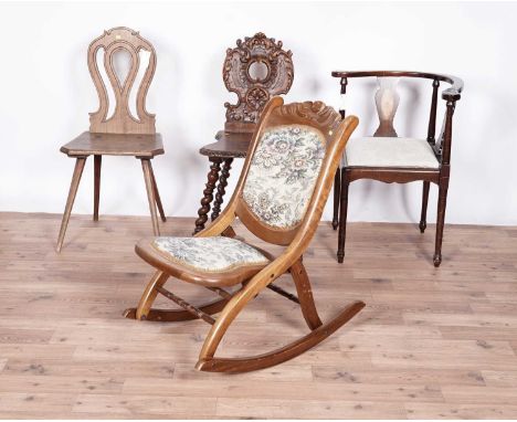 An early 20th Century carved mahogany folding rocking chair, with woven floral unholstered seats and back rest; together with