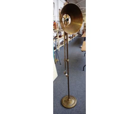 A brass adjustable standard lamp, 20th century, with conical sheet brass shade, weighted base and loop handle, 177cm high.  