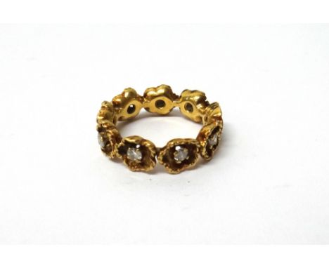 A gold and diamond set full eternity ring, designed as a row of flowerheads, each centred by a circular cut diamond, ring siz