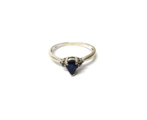 A white gold, sapphire and diamond ring, claw set with the pear shaped sapphire at the centre, between circular cut diamond s