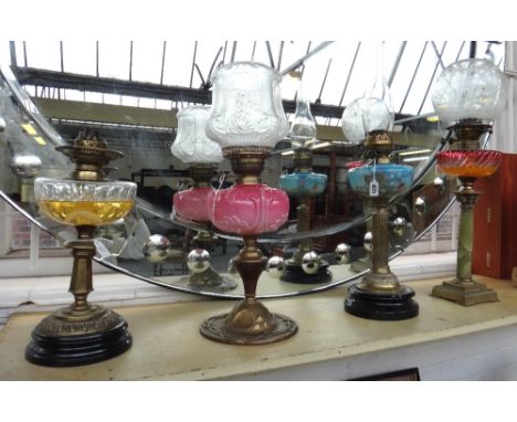A Victorian oil lamp with a painted blue glass reservoir, fluted brass column and an ebonised pottery base, another with reli