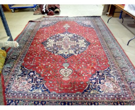 A Tabriz carpet, the claret red field with central blue and white Coptic cross design medallion within similar spandrels and 