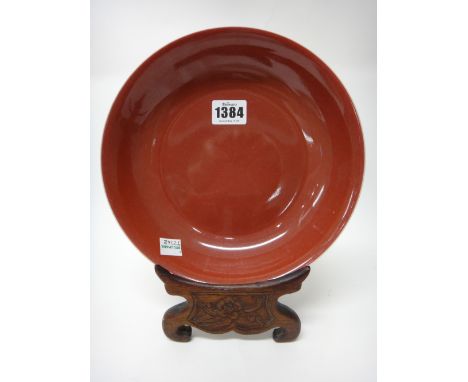 A Chinese copper-red glazed saucer dish, blue Daoguang seal mark and possibly of the period, 20.5cm.diameter, wood stand.