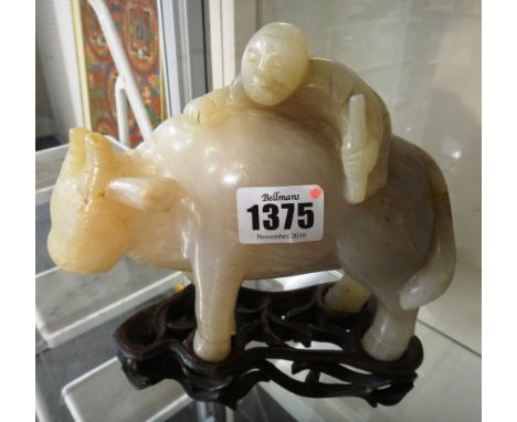 A Chinese jade group of a boy on a buffalo, 20th century, the stone of cream and light brown tone with russet inclusions, 14.