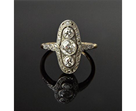 A gold and diamond set ring, mounted with three cushion shaped diamonds to the centre within a serpentine surround, mounted w