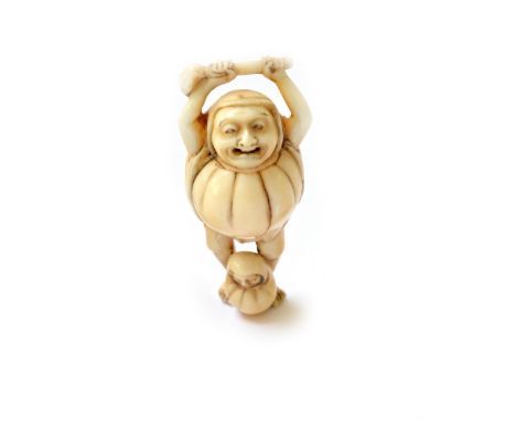 A Japanese ivory netsuke of Daruma, 19th century, carved standing holding a fly whisk above his head, a Daruma doll at his fe