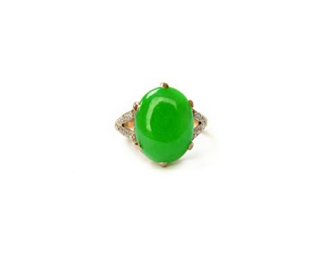 A gold and platinum, jade and diamond set ring, claw set with an oval cabochon jade, between diamond set 'V' shaped shoulders