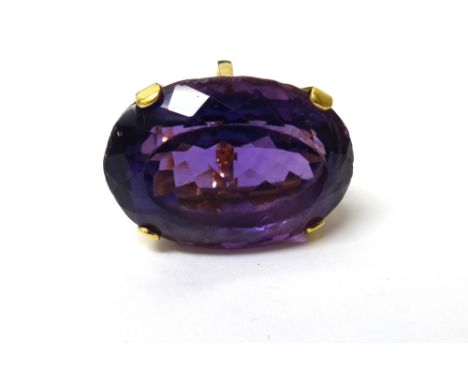 An 18ct gold ring, claw set with a large oval cut amethyst, London 1986, ring size K and a half.