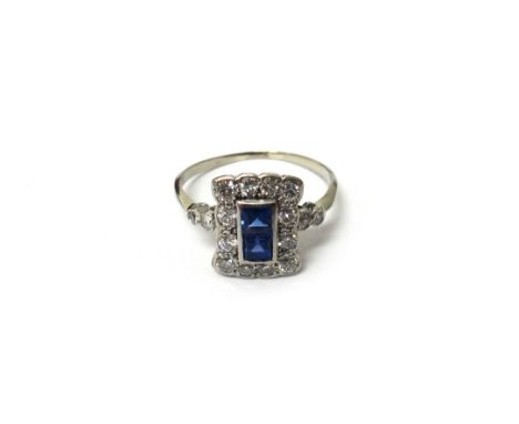 A sapphire and diamond ring, in a rectangular panel shaped design, mounted with two square cut sapphires to the centre, withi