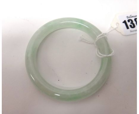 A Chinese jade bangle, the stone of pale celadon tone with apple green and white inclusions, 7.5cm. to outer rim.