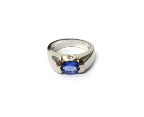 A white gold, tanzanite and diamond set three stone ring, mounted with an oval cut tanzanite, each side of the mount set with