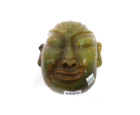 A Chinese jade mask of Buddha, the stone of green colour with russet and grey inclusions, the nostrils pierced, 16cm.high.