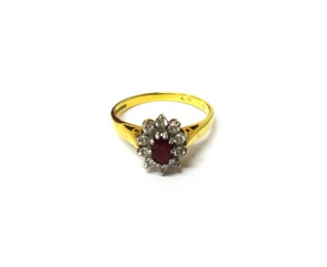 An 18ct gold, ruby and diamond set oval cluster ring, claw set with the oval cut ruby at the centre, within a surround of ten