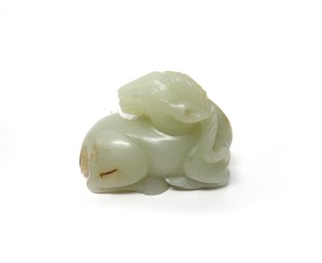 A Chinese pale celadon jade ram, the animal carved in recumbent pose with head turned across its back, the stone with russet 