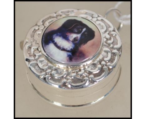 A silver novelty tape measure with embossed case and enamel pictorial image of a dog. 3cms long