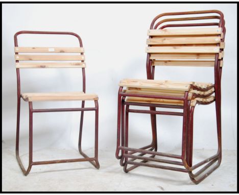 A stack of vintage mid century Industrial / school hall stacking chairs being raised on tubular metal frames with recently ne