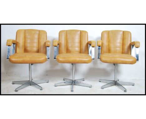A set of three retro 20th century salon / barbers swivel chairs. Having a beige button back vinyl upholstery, reclining back 