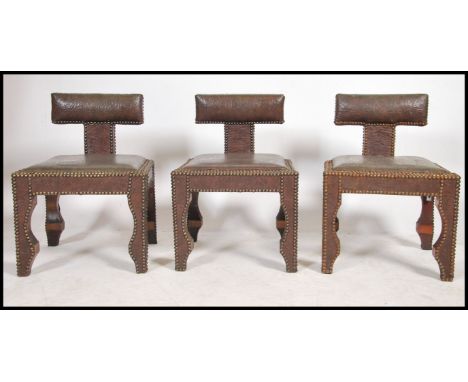 A set of three 20th century Moroccan carved hardwood leaher opium stools- dining chairs. Having a T-shaped carved rest with s