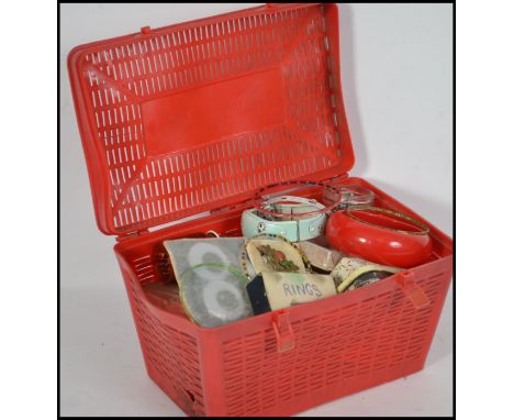 A vintage 1970's red plastic sewing box of picnic hamper form containing many items of costume jewellery and beads etc