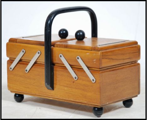 A vintage retro 20th century metamorphic sewing work box with an ebonised handle atop. 
