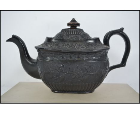 A 19th century Victorian black basalt ceramic teapot being decorated with floras and scroll work.  Of soft cube form with emb