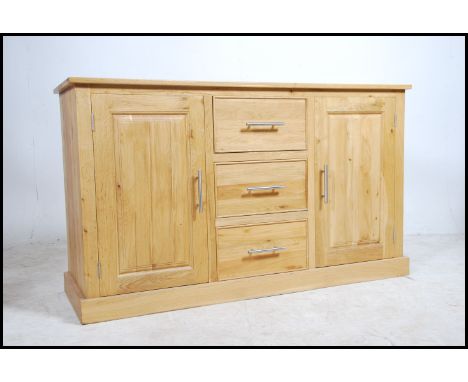 A contemporary light oak sideboard fitted with three drawers and two cabinets