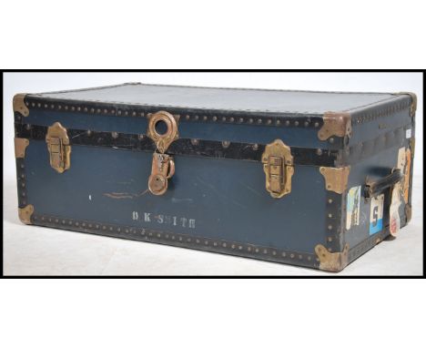 A mid century vintage large blue steamer trunk chest having clasp handles with blue panel body adorned with shipping labels. 