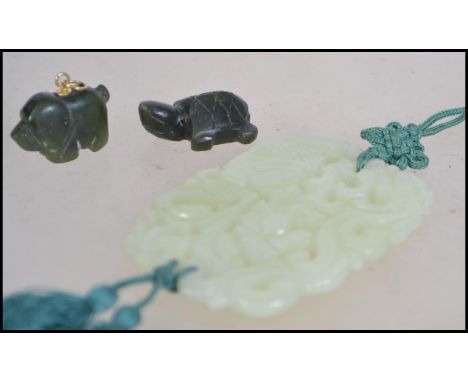 A collection of Chinese carved Jade pieces .  A large pendant carved with scrolls and flora's with a silk cord along with two