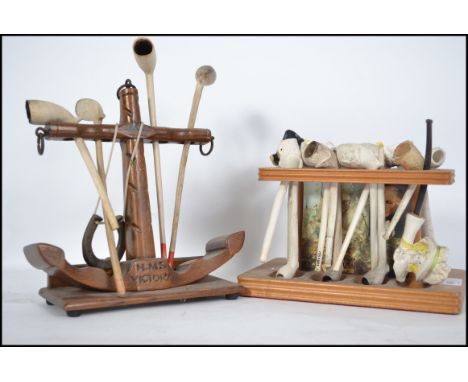 A collection of vintage clay smoking pipes being set within two stands both with HMS Victory notation. The pipes, some being 